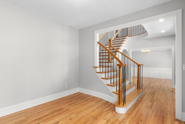 stairs featuring hardwood / wood-style floors and a chandelier