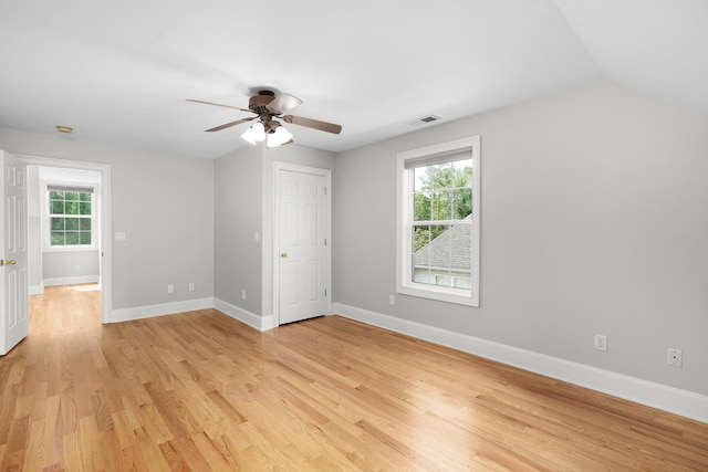 unfurnished bedroom featuring multiple windows, ceiling fan, light hardwood / wood-style flooring, and lofted ceiling