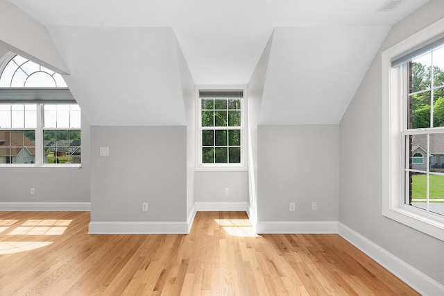 additional living space with vaulted ceiling and light hardwood / wood-style flooring