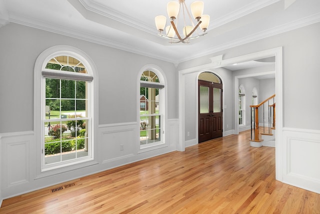 foyer with a healthy amount of sunlight, light hardwood / wood-style floors, and ornamental molding