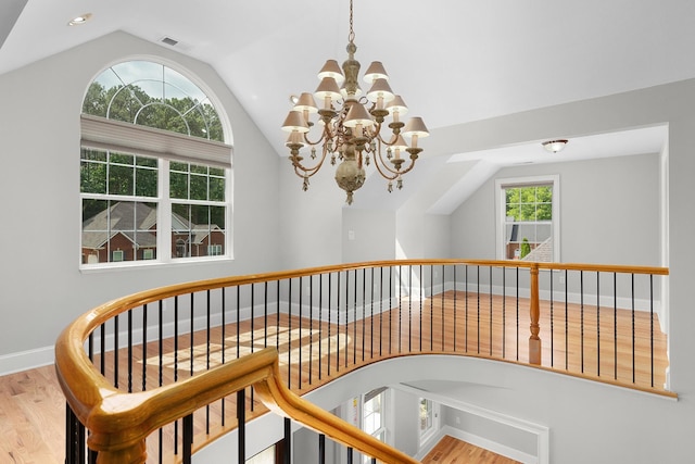 stairs with hardwood / wood-style floors, a chandelier, and lofted ceiling