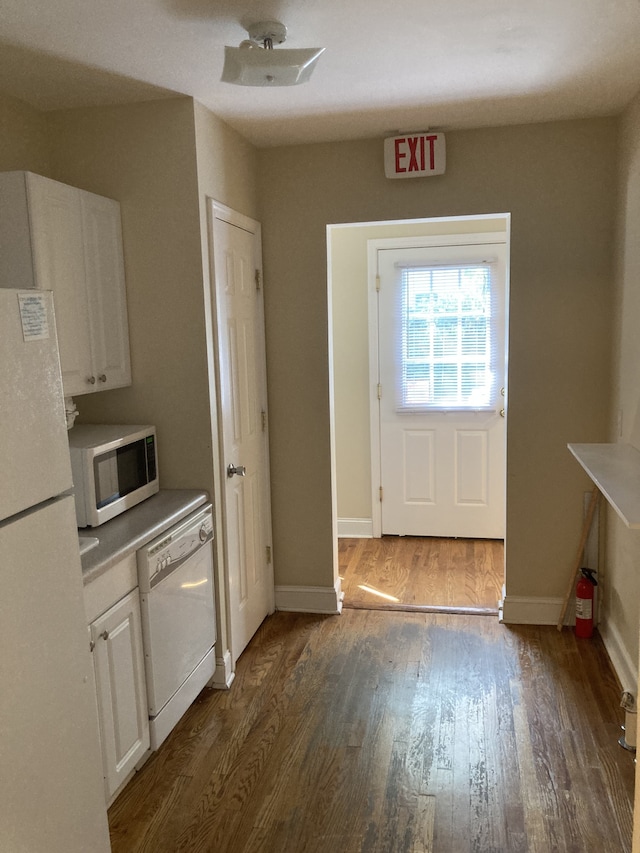 kitchen featuring white appliances, white cabinetry, and dark wood-type flooring