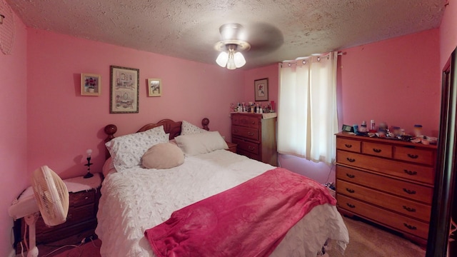 bedroom with ceiling fan, carpet floors, and a textured ceiling