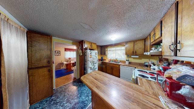 kitchen featuring butcher block countertops, sink, white appliances, and a textured ceiling