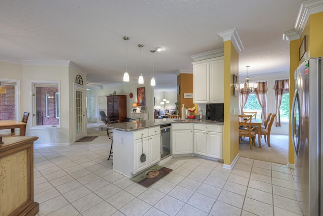 kitchen with a kitchen breakfast bar, kitchen peninsula, stainless steel fridge, crown molding, and decorative light fixtures