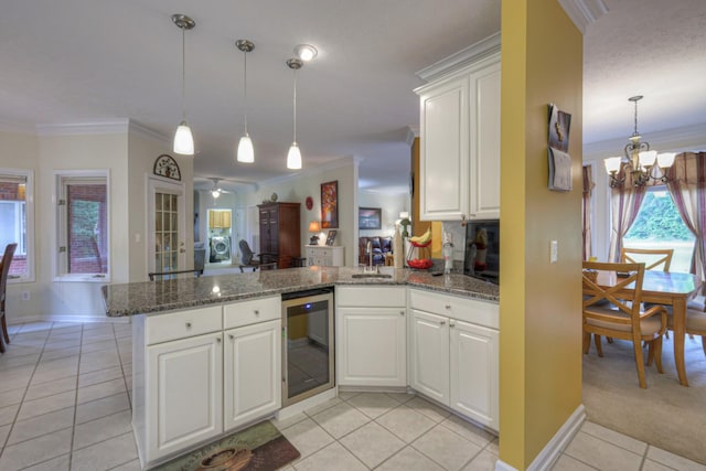 kitchen featuring white cabinets, kitchen peninsula, hanging light fixtures, and crown molding