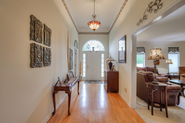 foyer entrance with light hardwood / wood-style floors and crown molding