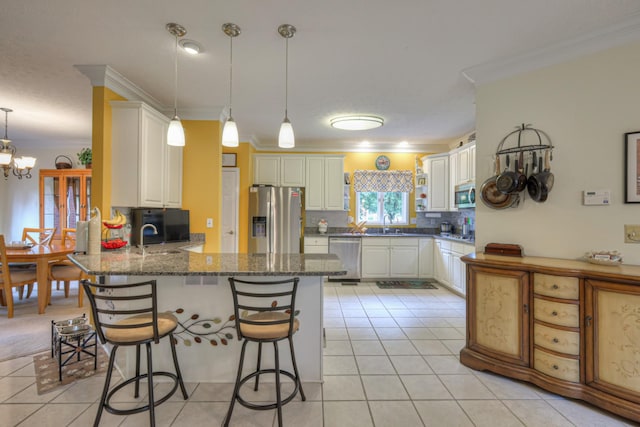 kitchen with tasteful backsplash, kitchen peninsula, dark stone countertops, appliances with stainless steel finishes, and ornamental molding