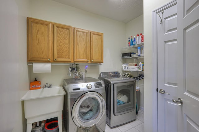 clothes washing area featuring cabinets, a textured ceiling, sink, independent washer and dryer, and light tile patterned flooring