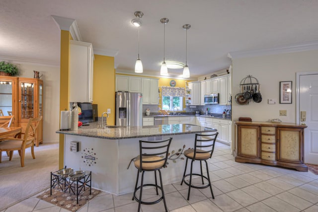 kitchen featuring a breakfast bar, kitchen peninsula, crown molding, and appliances with stainless steel finishes