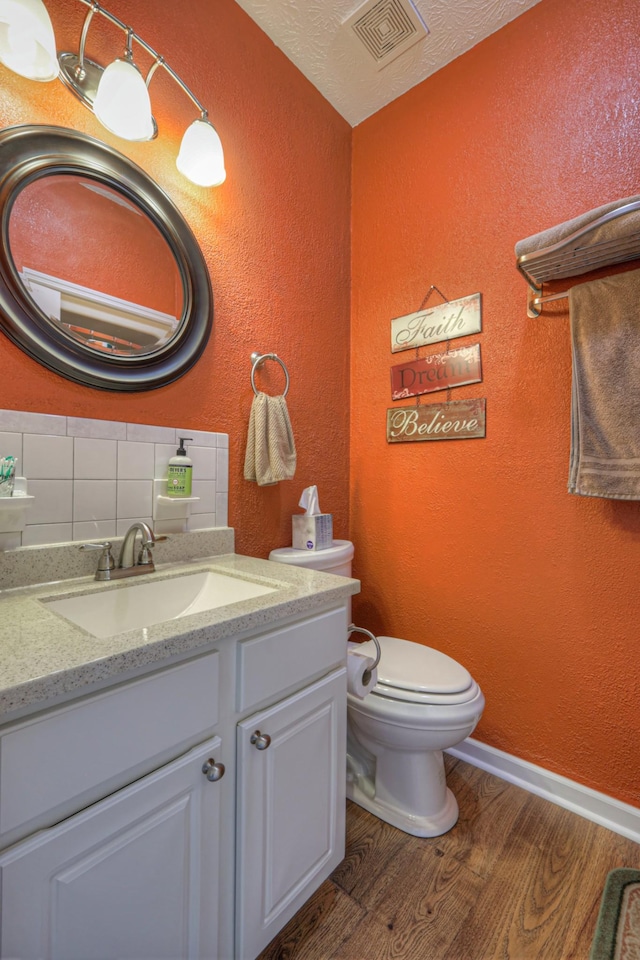 bathroom featuring hardwood / wood-style floors, vanity, backsplash, toilet, and a textured ceiling