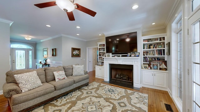 living room featuring light hardwood / wood-style flooring, ceiling fan, and ornamental molding