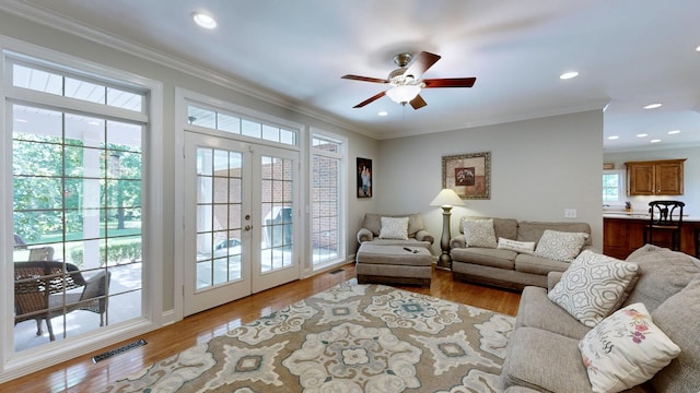 living room with ceiling fan, ornamental molding, light hardwood / wood-style flooring, and french doors