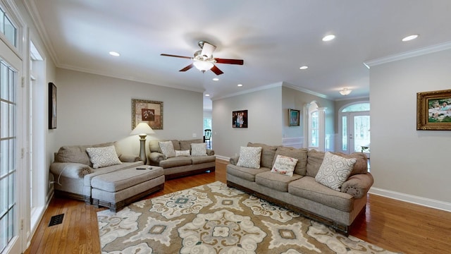 living room featuring hardwood / wood-style flooring, ceiling fan, and crown molding