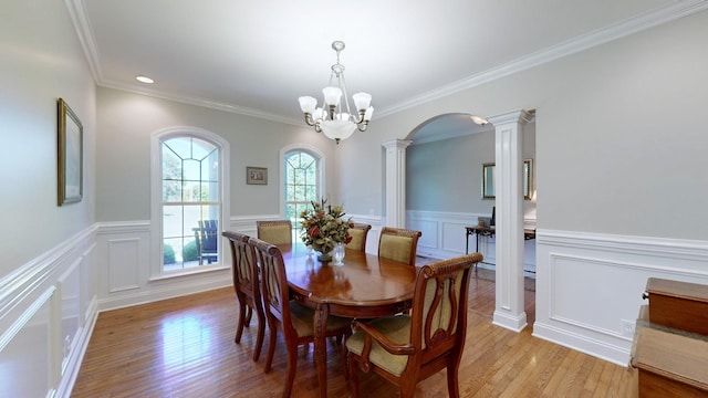 dining room featuring a chandelier, light wood-type flooring, ornate columns, and crown molding