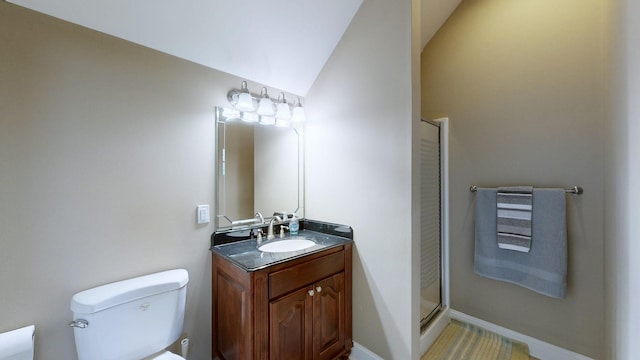 bathroom featuring vanity, toilet, a shower with door, and vaulted ceiling