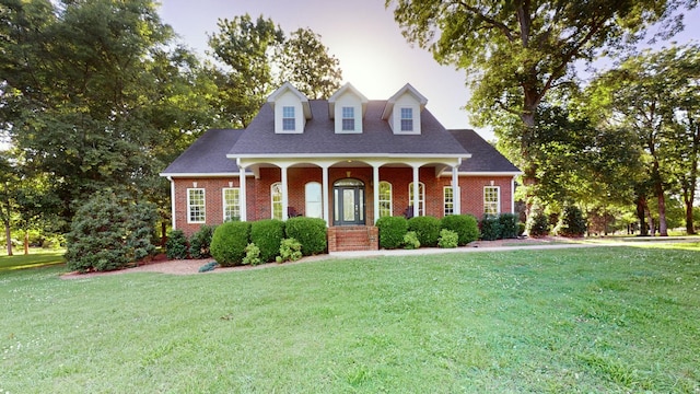 cape cod house featuring a front lawn and covered porch