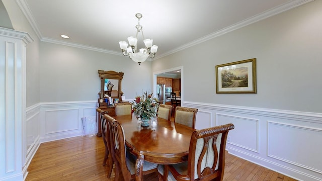 dining space with light wood-type flooring, crown molding, and a notable chandelier