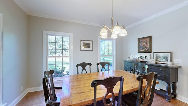 dining area featuring light hardwood / wood-style flooring, ornamental molding, and a notable chandelier