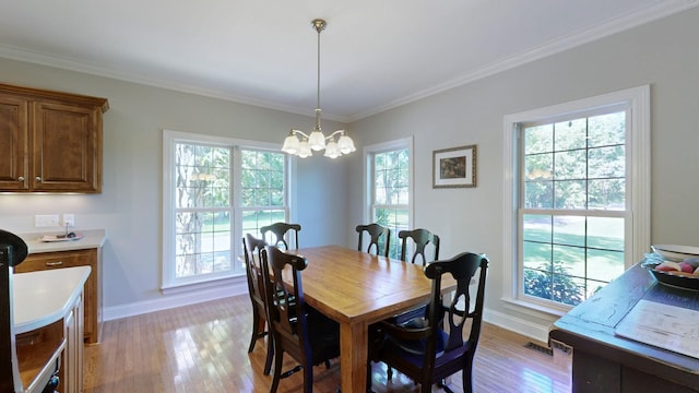 dining room with a notable chandelier, ornamental molding, and light hardwood / wood-style flooring