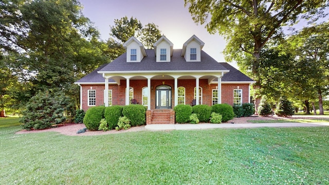 new england style home featuring a lawn and covered porch