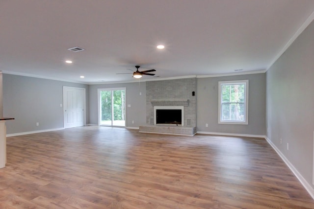 unfurnished living room with a brick fireplace, ceiling fan, crown molding, and light hardwood / wood-style flooring