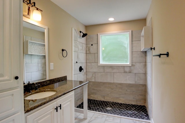 bathroom with a tile shower and vanity