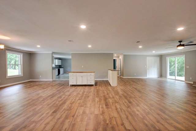 unfurnished living room with ceiling fan, crown molding, and light hardwood / wood-style flooring