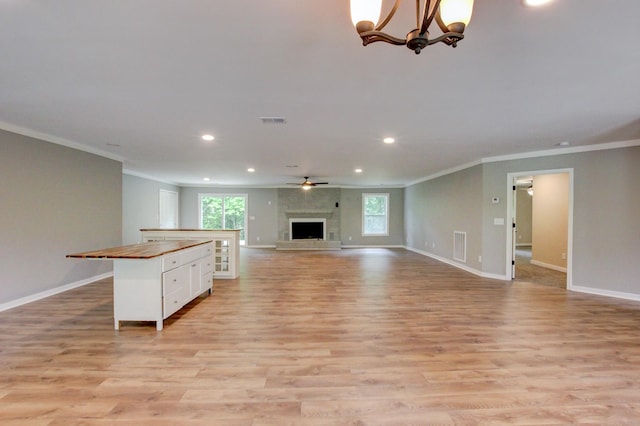 unfurnished living room featuring a wealth of natural light, crown molding, and light hardwood / wood-style floors