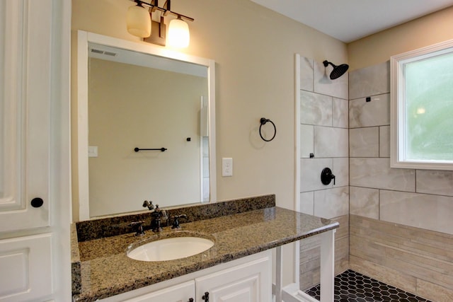 bathroom with tiled shower and vanity