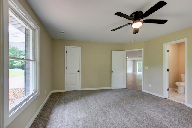 unfurnished bedroom with light carpet, ensuite bathroom, and ceiling fan