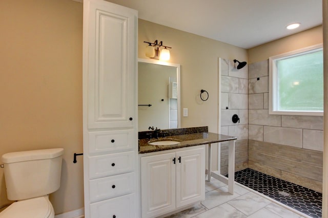 bathroom with vanity, toilet, and tiled shower