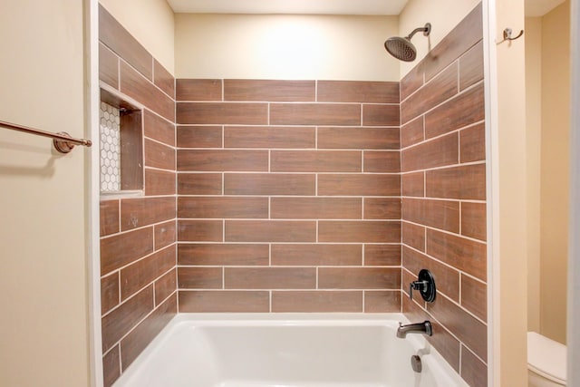 bathroom featuring tiled shower / bath combo and toilet