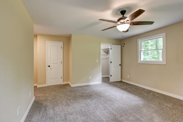 unfurnished bedroom featuring a spacious closet, ceiling fan, and carpet floors