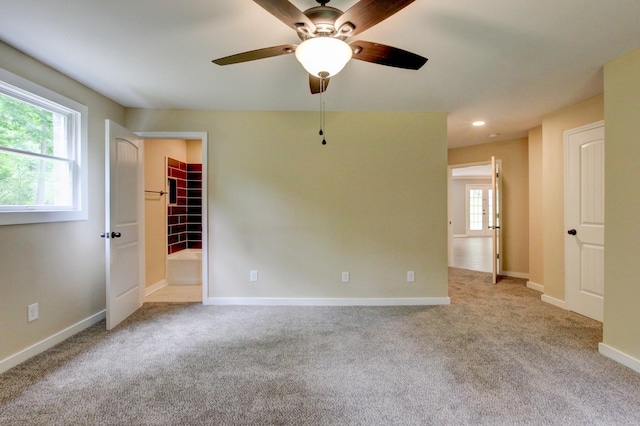 unfurnished room featuring light carpet, a wealth of natural light, and ceiling fan