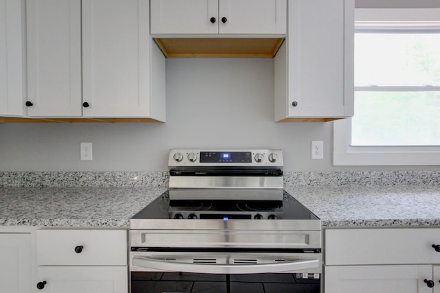 kitchen with stainless steel range with electric stovetop, white cabinets, and light stone countertops