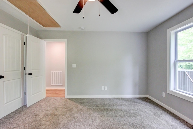 empty room with ceiling fan, a healthy amount of sunlight, and light colored carpet