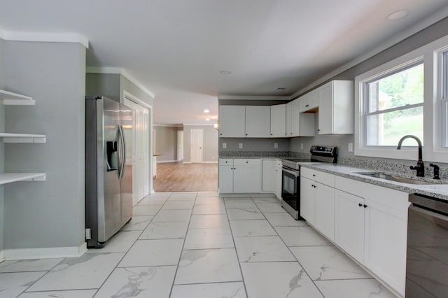 kitchen with sink, ornamental molding, appliances with stainless steel finishes, light stone counters, and white cabinetry