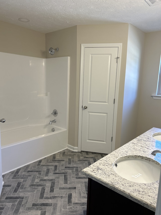 bathroom featuring bathing tub / shower combination, vanity, and a textured ceiling