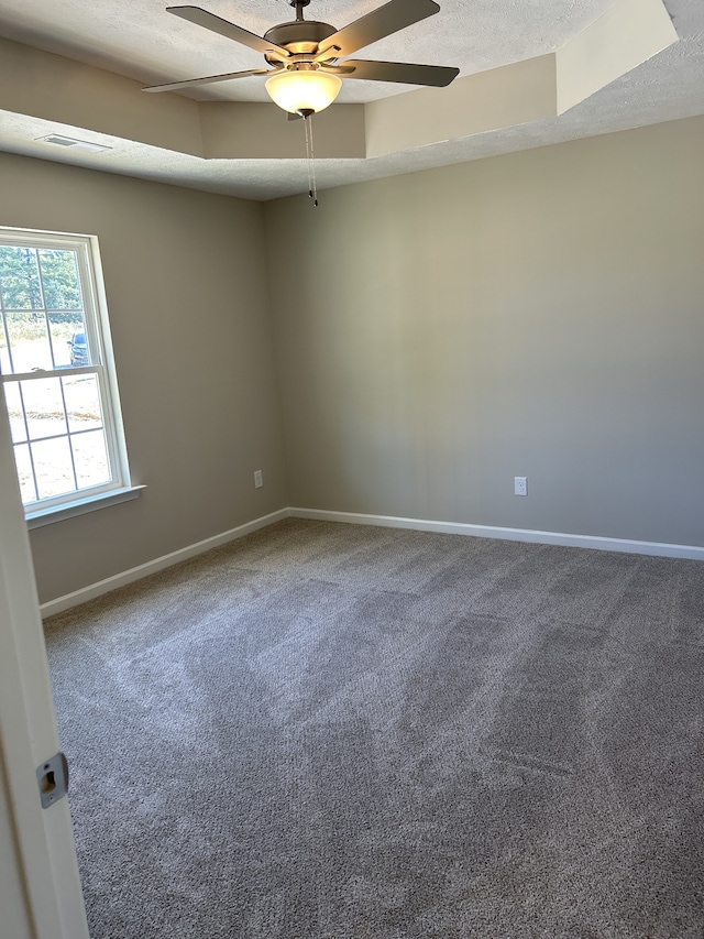 unfurnished room with ceiling fan, a tray ceiling, carpet, and a textured ceiling