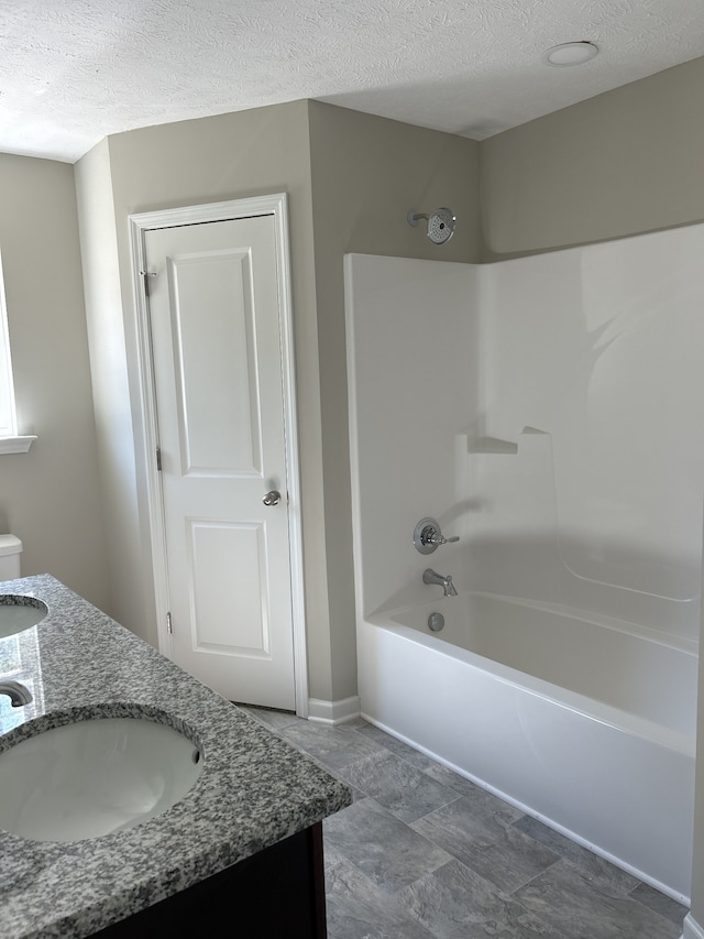 bathroom with vanity, a textured ceiling, and  shower combination