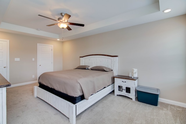 bedroom featuring light carpet, a raised ceiling, and ceiling fan