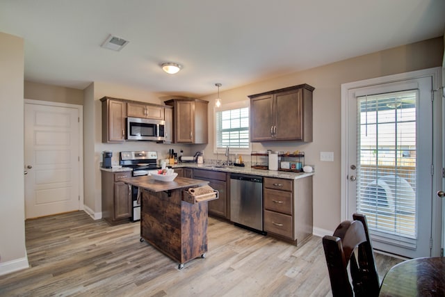 kitchen featuring decorative light fixtures, a center island, stainless steel appliances, and light hardwood / wood-style floors