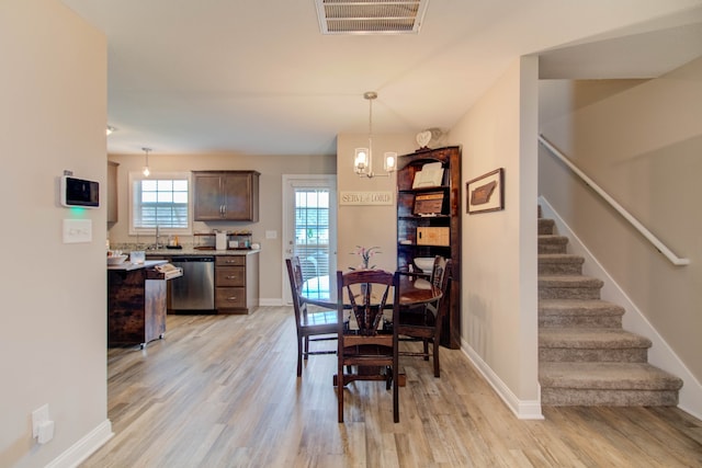 dining space with light hardwood / wood-style floors and an inviting chandelier