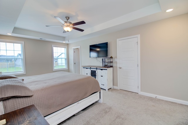 carpeted bedroom featuring a raised ceiling and ceiling fan