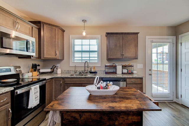 kitchen with sink, butcher block countertops, light hardwood / wood-style floors, a kitchen island, and appliances with stainless steel finishes