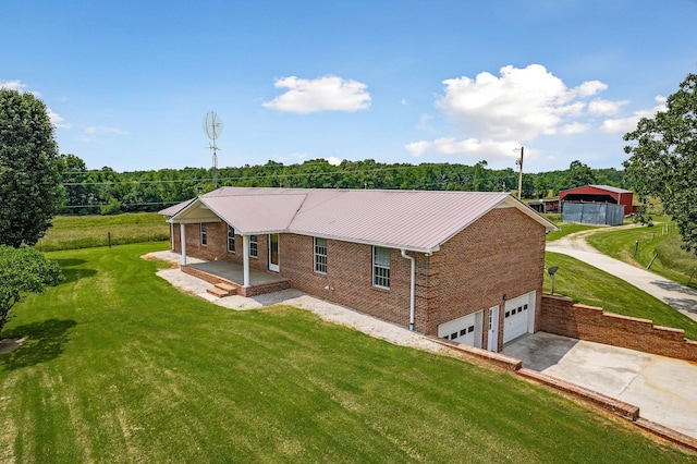 rear view of house featuring brick siding, metal roof, a garage, a yard, and driveway