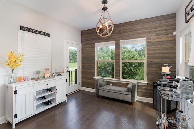 sitting room featuring wood walls, dark wood-type flooring, and an inviting chandelier