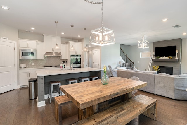 dining space featuring a large fireplace, dark hardwood / wood-style floors, and a notable chandelier