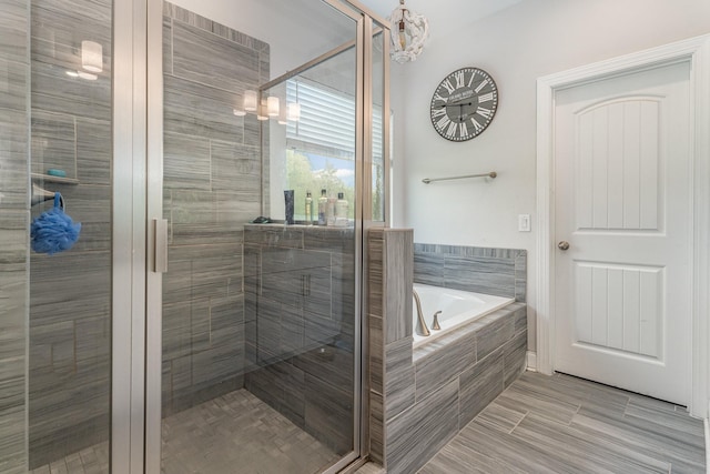 bathroom featuring separate shower and tub and an inviting chandelier